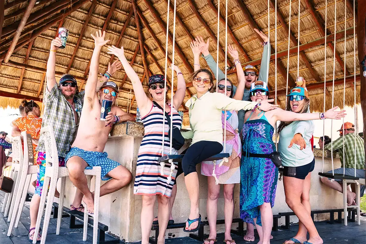 Guests posing with hands up sitting at a beachside bar area.