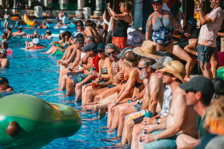 Guests sitting on the edge of the pool, laughing and talking together.