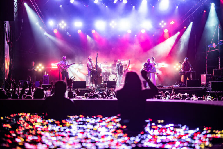 Guests in an Oceanfront Suite swim up pool watching a concert at the Beach Stage at night.
