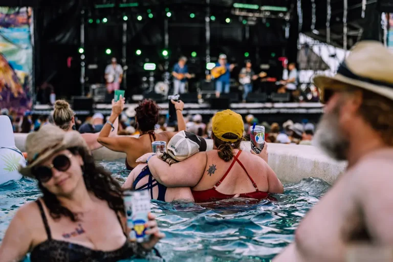 Guests in an Oceanfront Suite swim up pool watching a concert at the Beach Stage.