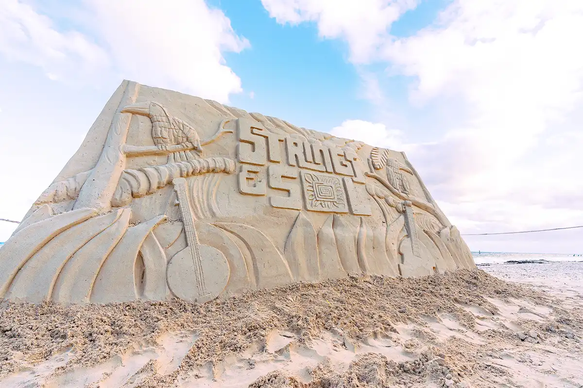 A Strings & Sol sand sculpture displaying the logo and art for the event.