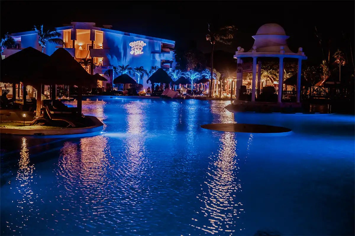 Main pool area at night with resort room building in background.