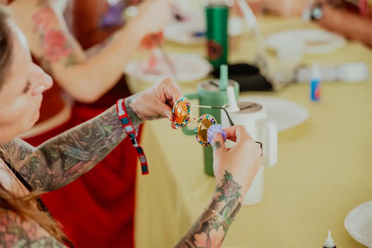 Guest decorating sunglasses at table during activity session.