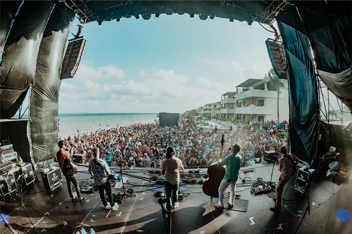 View from beach stage looking out over crowd with ocean beside them.