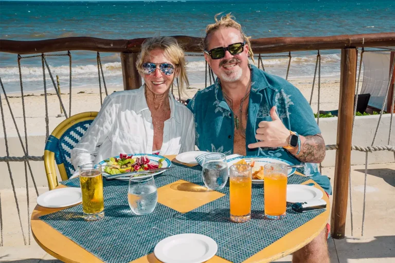 Guests seated beachside, dining at a resort restaurant.