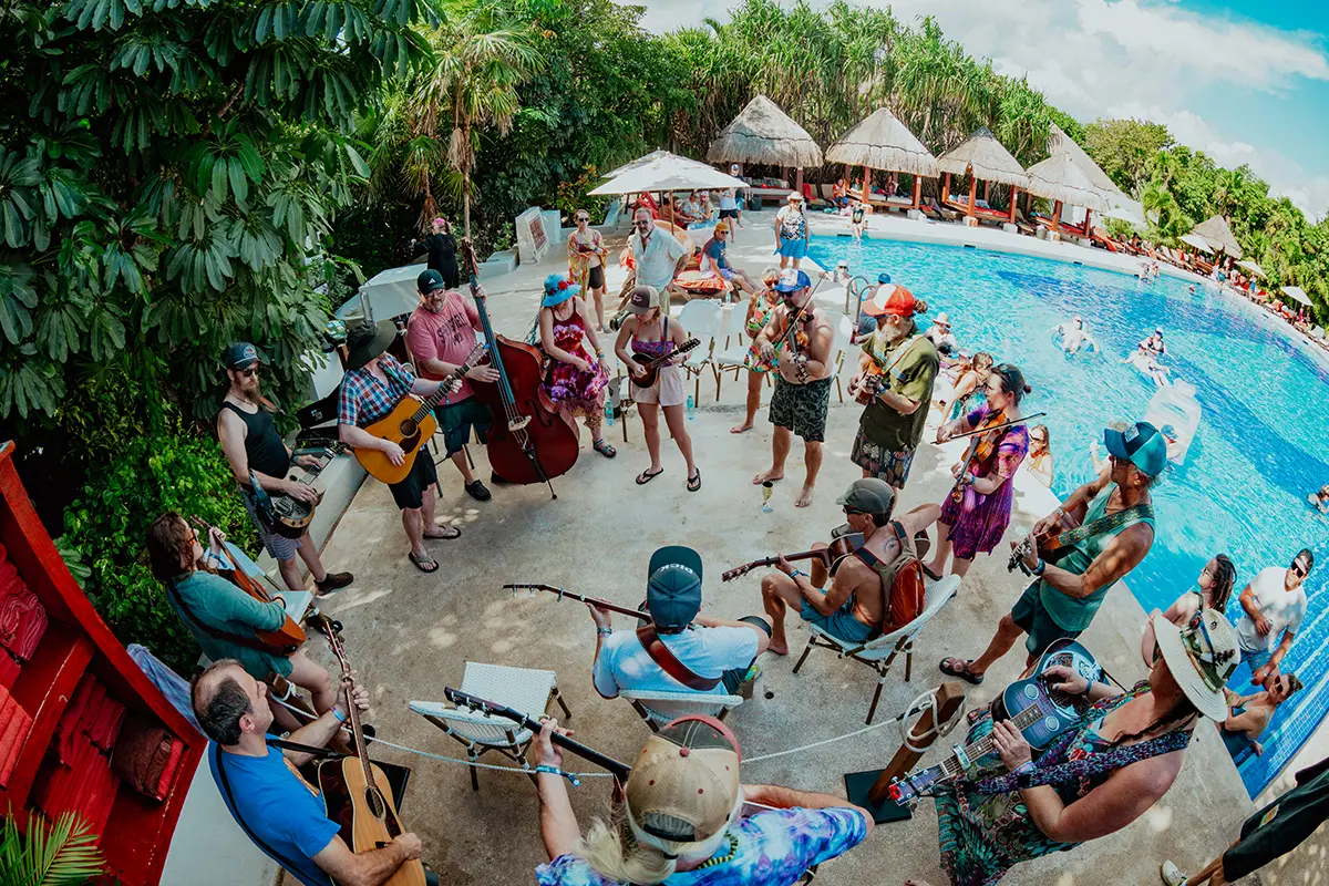 Guests playing instruments together during fan jam session by the pool.