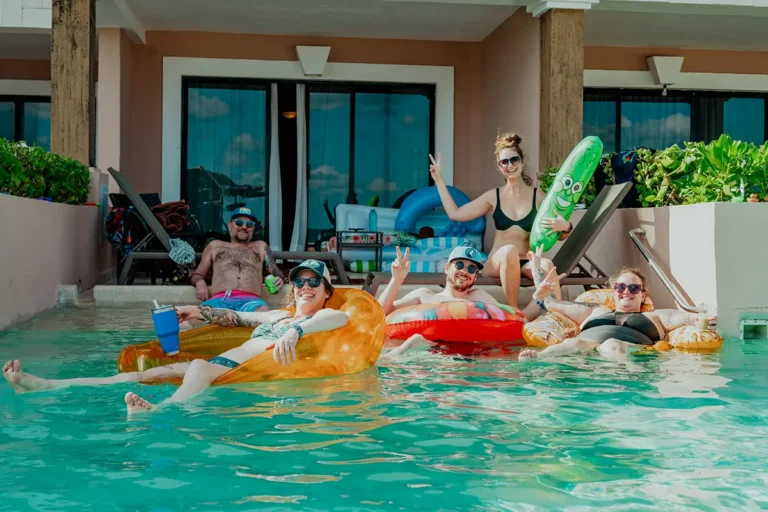 Group photo of guests lounging on pool inflatables in a swim up pool attached to an Oceanfront Suite.